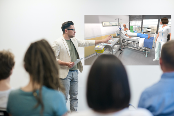Formateur qui présente le simulateur de pose d'aiguille sur chambre à cathéter implantable à ses étudiants